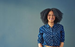 Studio shot of a happy young woman posing against a gray background