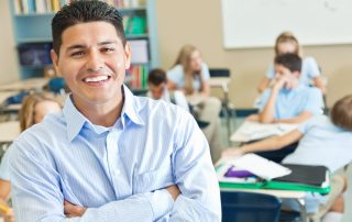 Smiling teacher in his classroom full of students.