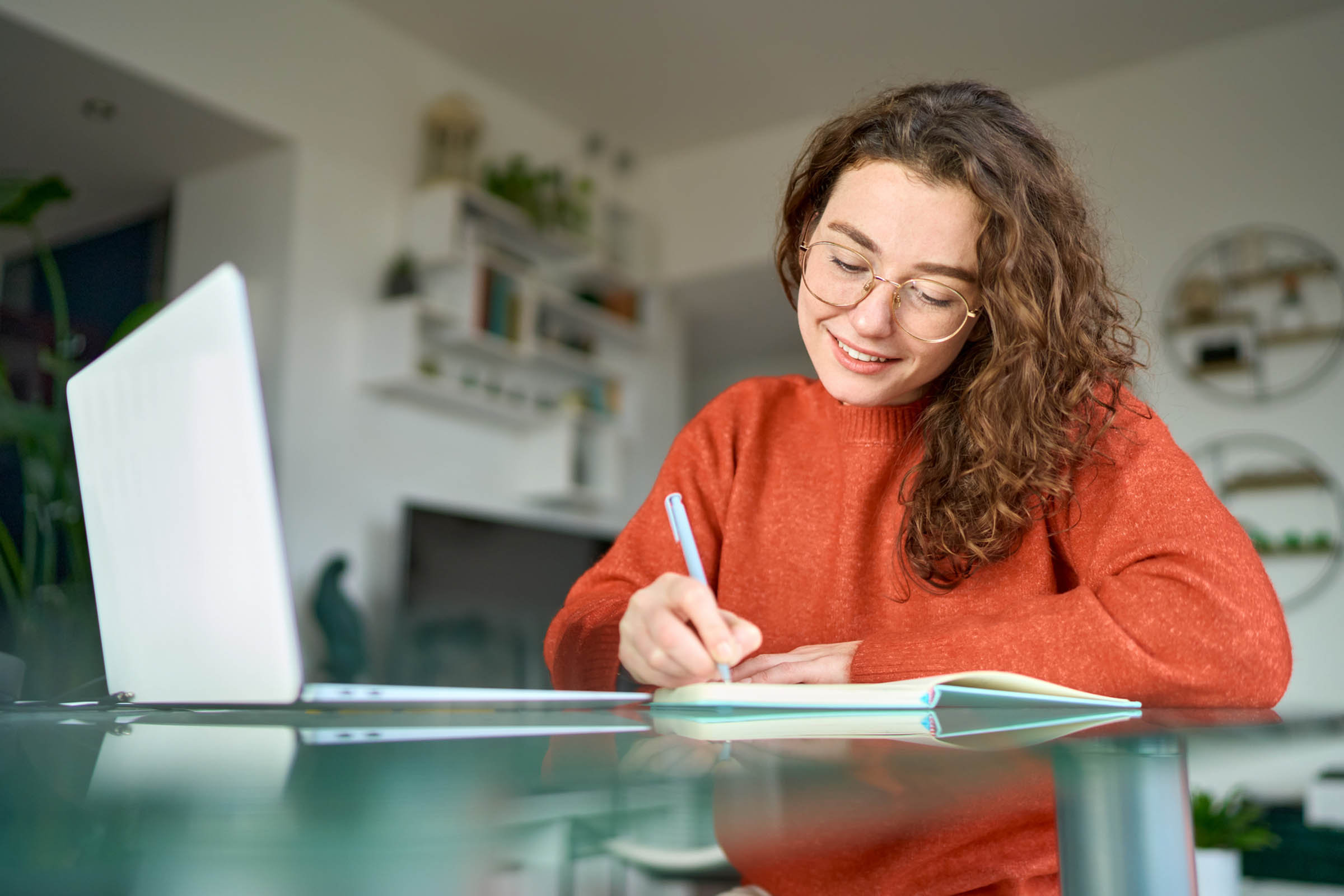 Young smiling woman student using laptop watching webinar writing at home. woman doing Continuing education courses at home